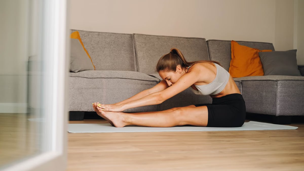 Woman in activewear stretching on yoga mat at home, promoting a healthy lifestyle.